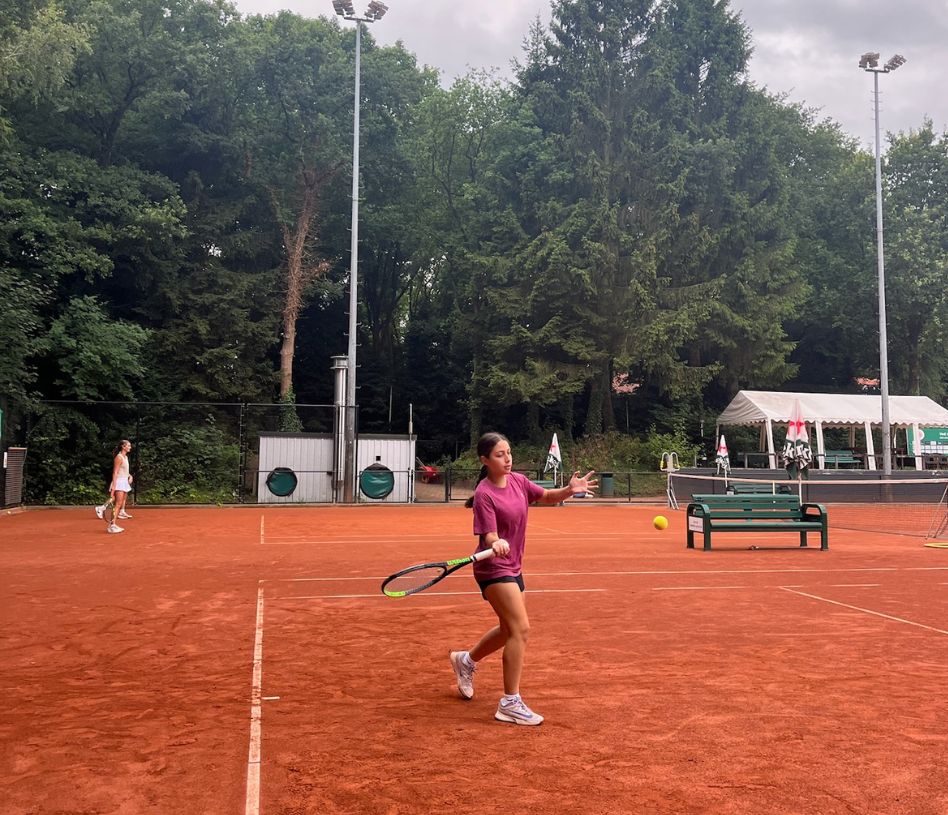 Girl hitting a forehand on a red clay court in the Netherlands